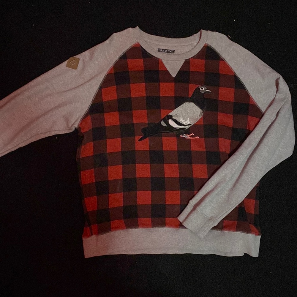 A red and gray plaid crewneck with pigeon as graphic design.